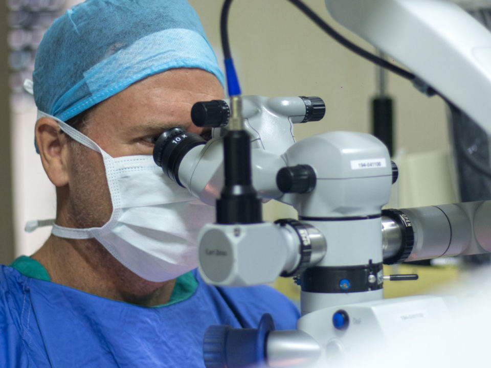 | Dr James Beatty Specialist eye surgeon in theatre using a microscope for delicate ophthalmic treatment